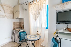 Una cucina compatta con piano cottura a gas, lavello e un piccolo angolo ristoro con tavolo e sedie.