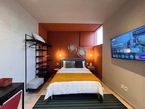 Ein Hotelzimmer mit einem Bett, einem an der Wand befestigten Fernseher, einem Kleiderschrank und einem kleinen Tisch.