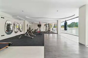 A modern gym with exercise equipment, large mirrors, and a punching bag. - Premium Penthouse with Luxury Amenities (Q.R.)