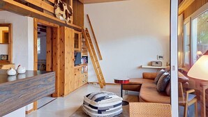 A cozy interior with a wooden staircase, a sofa, a dining table, and a television.