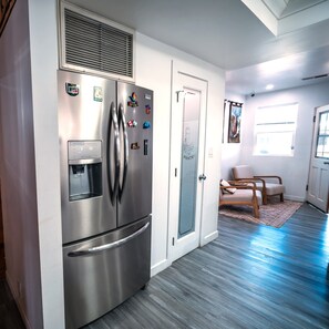 A modern kitchen with a stainless steel refrigerator, a water dispenser, and a pantry door.