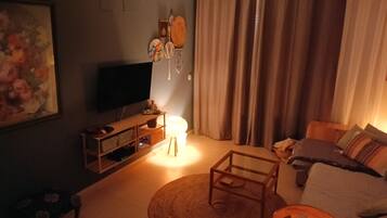 A living room with a television, a sofa, a coffee table, and a chair.