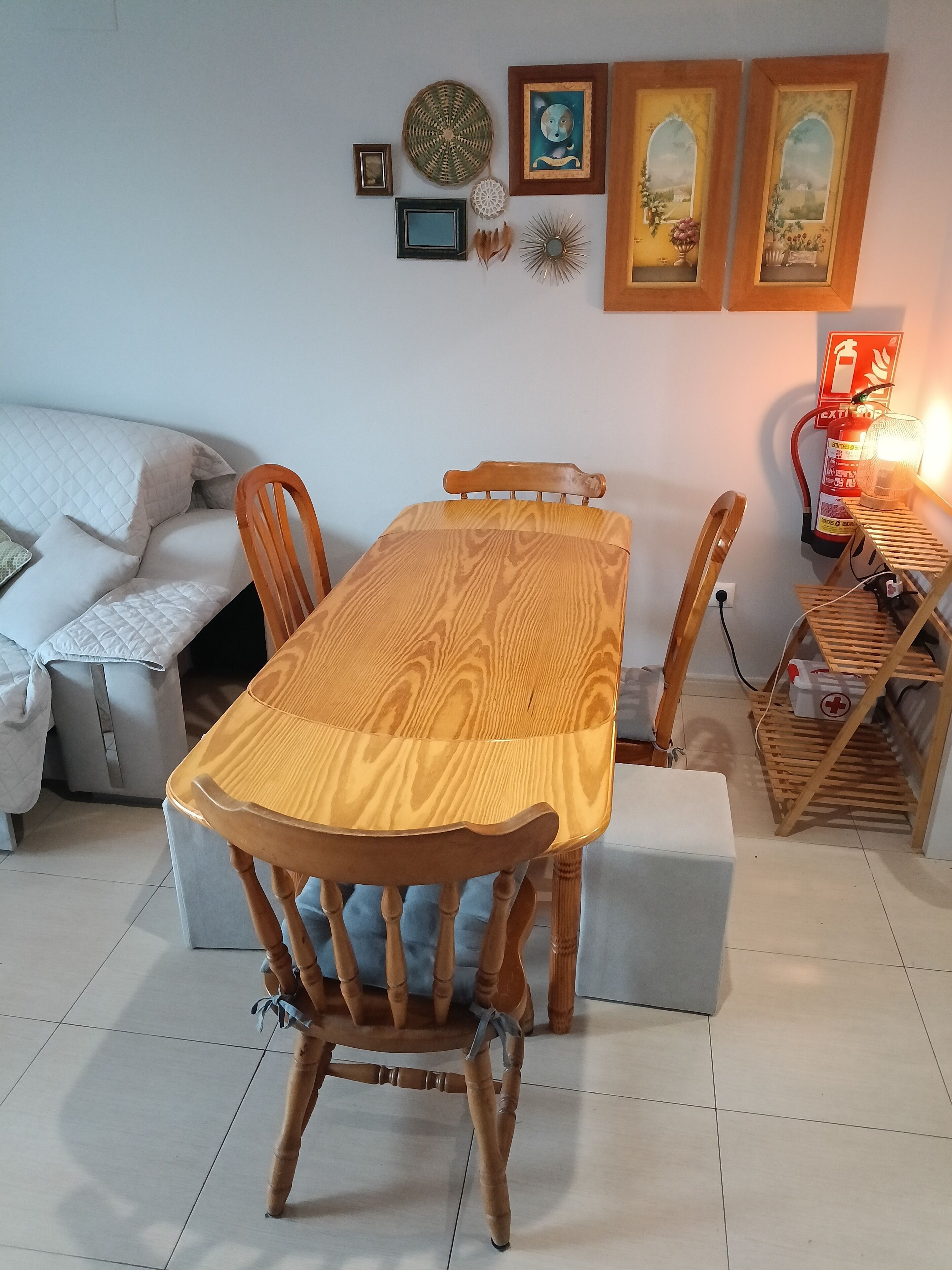 A dining area with a wooden table and chairs, a sofa, and wall-mounted decorations.