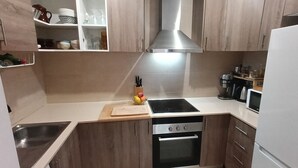 Ett modernt kök med träskåp, en rostfri köksfläkt, en inbyggd ugn och en mikrovågsugn.
