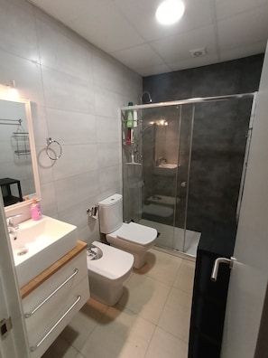 Une salle de bain moderne équipée de toilettes, d’un lavabo et d’une douche.
