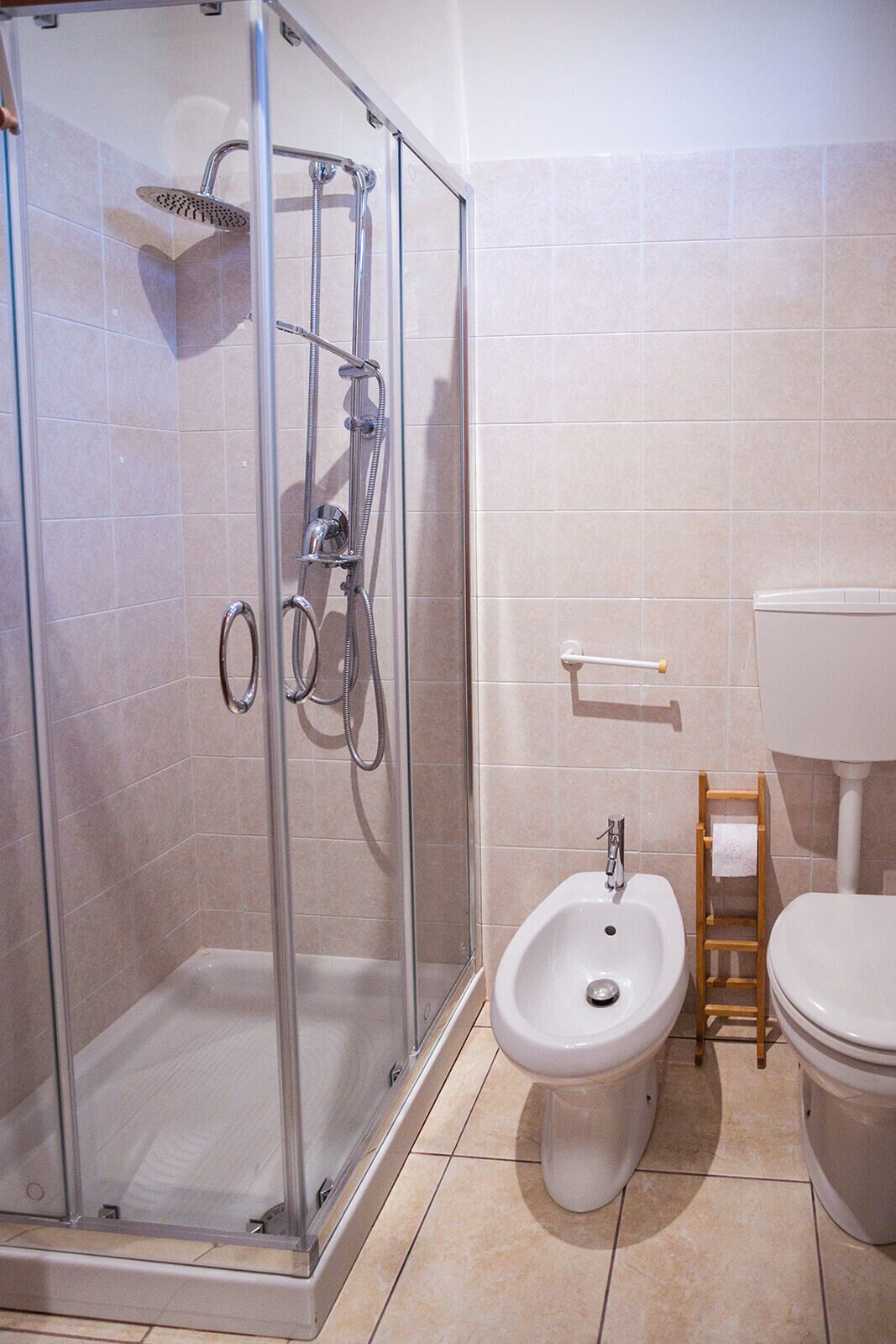 A bathroom with a glass-enclosed shower, a bidet, and a toilet.