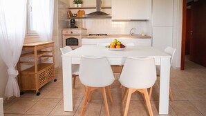 A modern kitchen with a white table, two chairs, a fruit bowl, and a coffee machine. - Mediterranea - Seaside Sicily Home with Veranda (Marina di Modica (Modica))