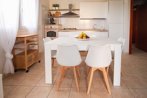 A modern kitchen with a white table, two chairs, a fruit bowl, and a coffee machine. - Mediterranea - Seaside Sicily Home with Veranda (Marina di Modica (Modica))