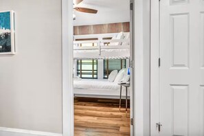 Ein Zimmer mit einem Etagenbett, einem Deckenventilator und einem Fenster mit Jalousien.