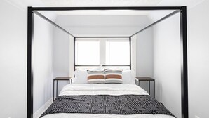 Ein modernes Zimmer mit einem Bett, zwei Nachttischen und einem Fenster.