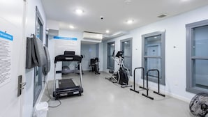 Uma academia com esteiras, elípticos e equipamentos de ginástica.