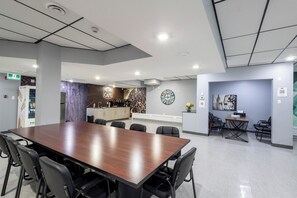 A modern conference room with a long table, chairs, a kitchenette, and a clock on the wall. - Regina (Regina)