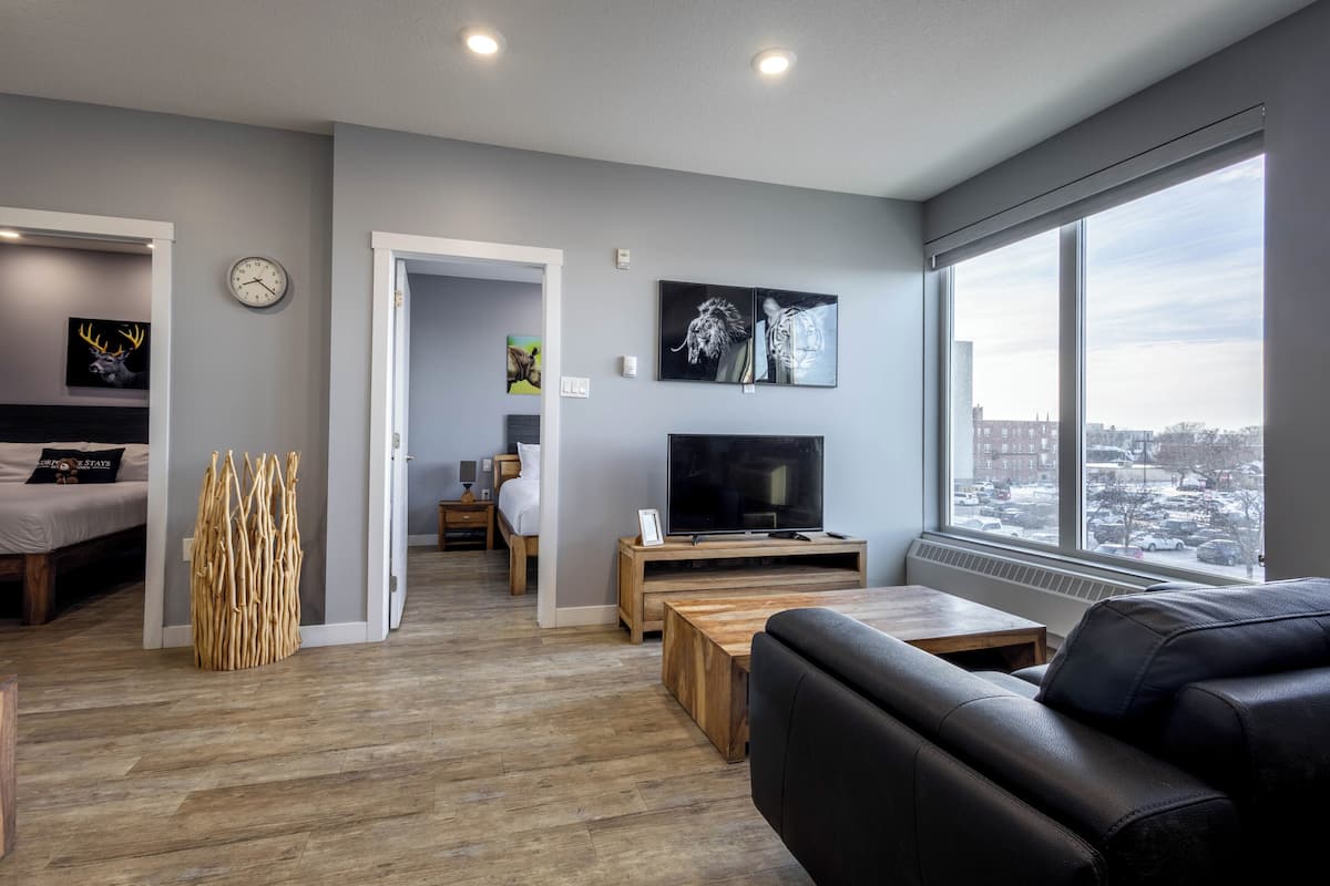 A modern living room with a sofa, TV, and large windows.