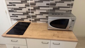 A kitchen with a microwave, a black induction cooktop, and a tiled backsplash.