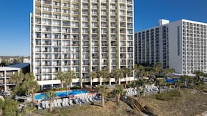 A high-rise hotel with multiple balconies, a swimming pool, and palm trees. - 2 Queens Oceanfront Room - Sea Crest Resort (Myrtle Beach)