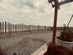 A pebbled deck with a wooden fence, a potted plant, and a cityscape in the background. - Ocean View - family Apartment- 15min Airport & Miraflores in San Miguel Lima (San Miguel)