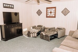 Una sala de estar con televisor, mueble de madera oscura y sofá color crema.