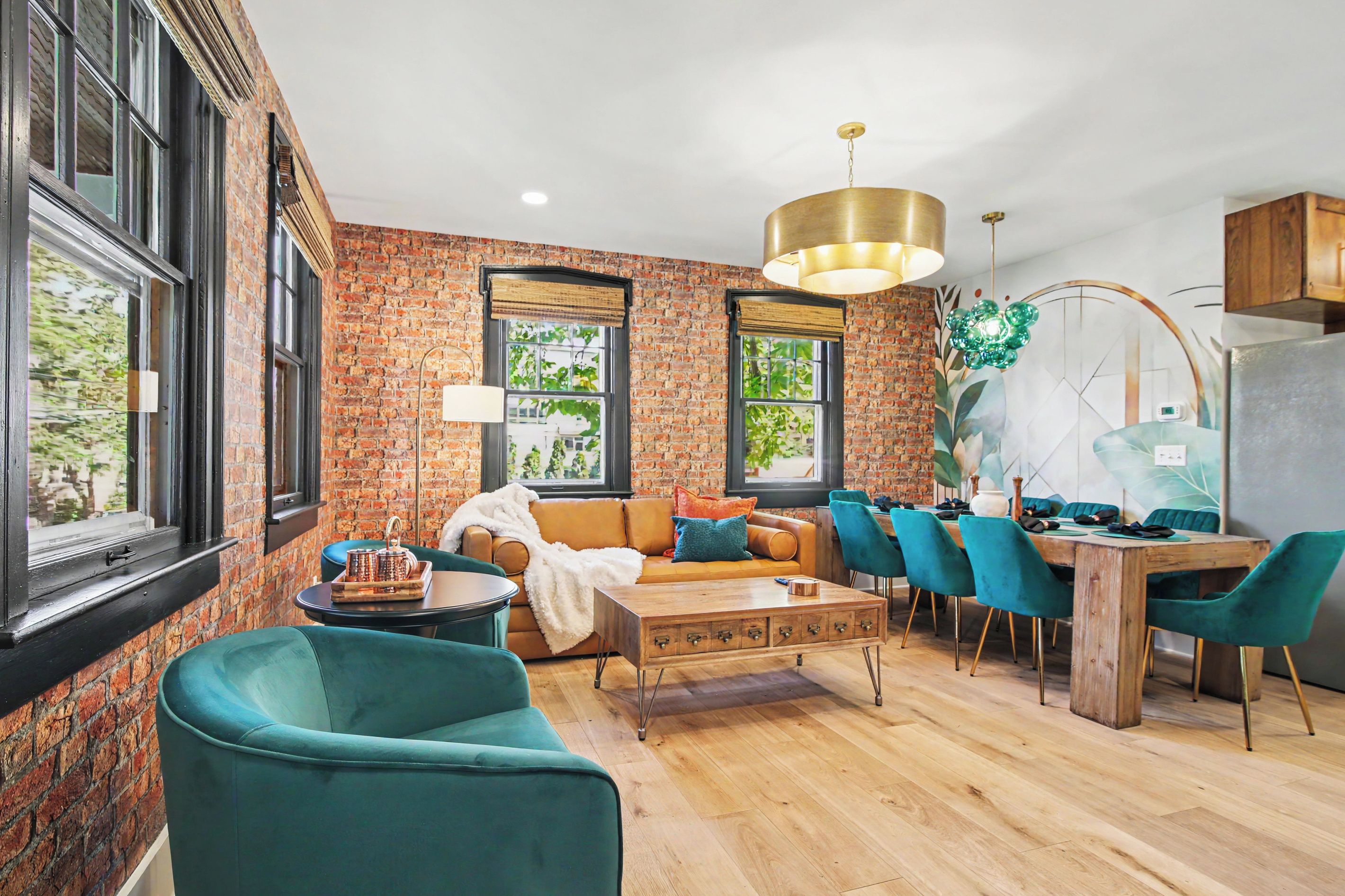 A modern living room with a brick wall, a sofa, a coffee table, and teal chairs.