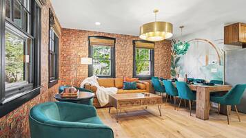 A modern living room with a brick wall, a sofa, a coffee table, and teal chairs.