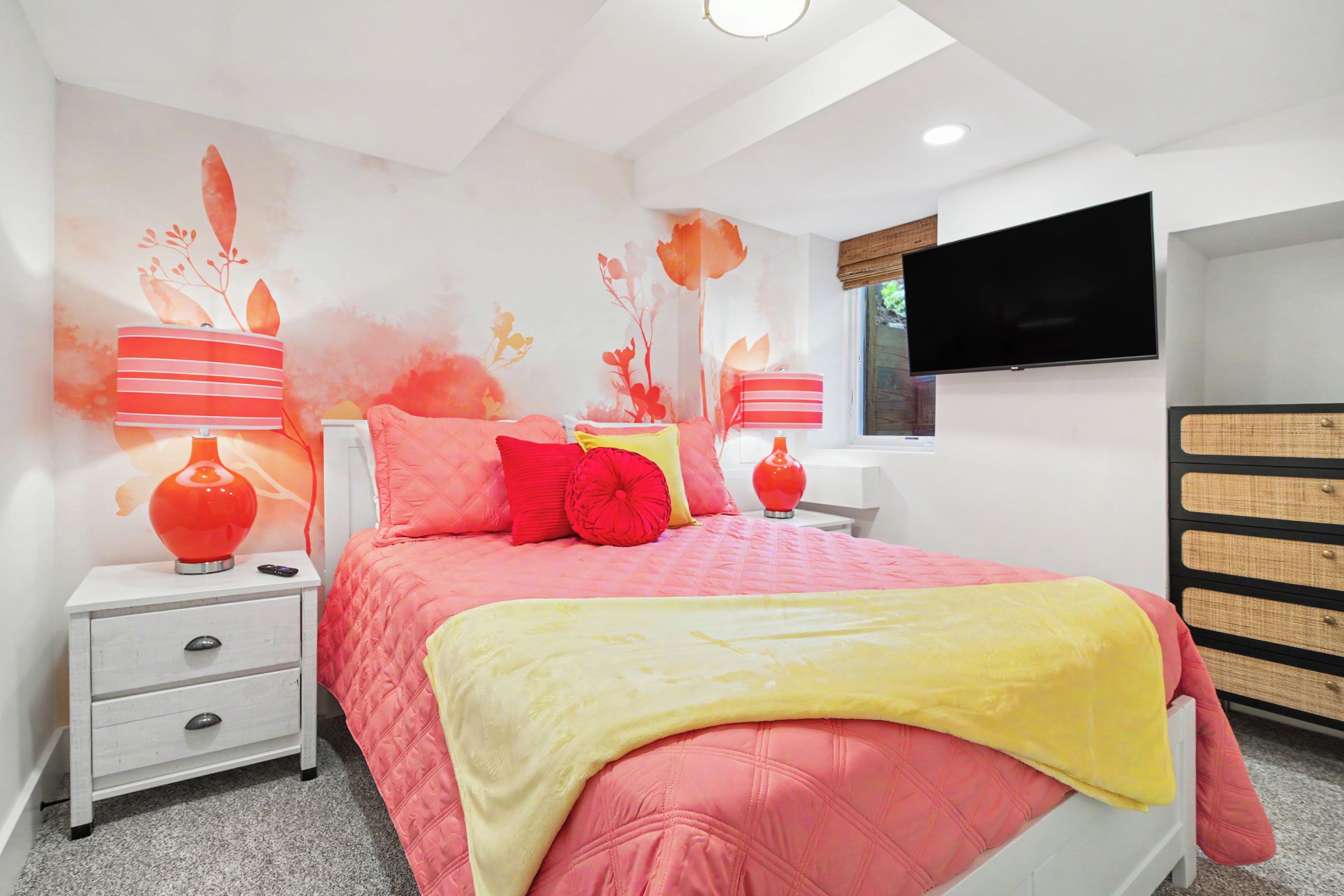 A bedroom with a bed, nightstands, a TV, and a dresser.