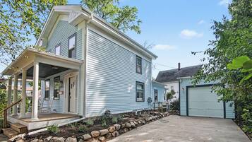 A two-story house with a porch, a garage, and a stone retaining wall.