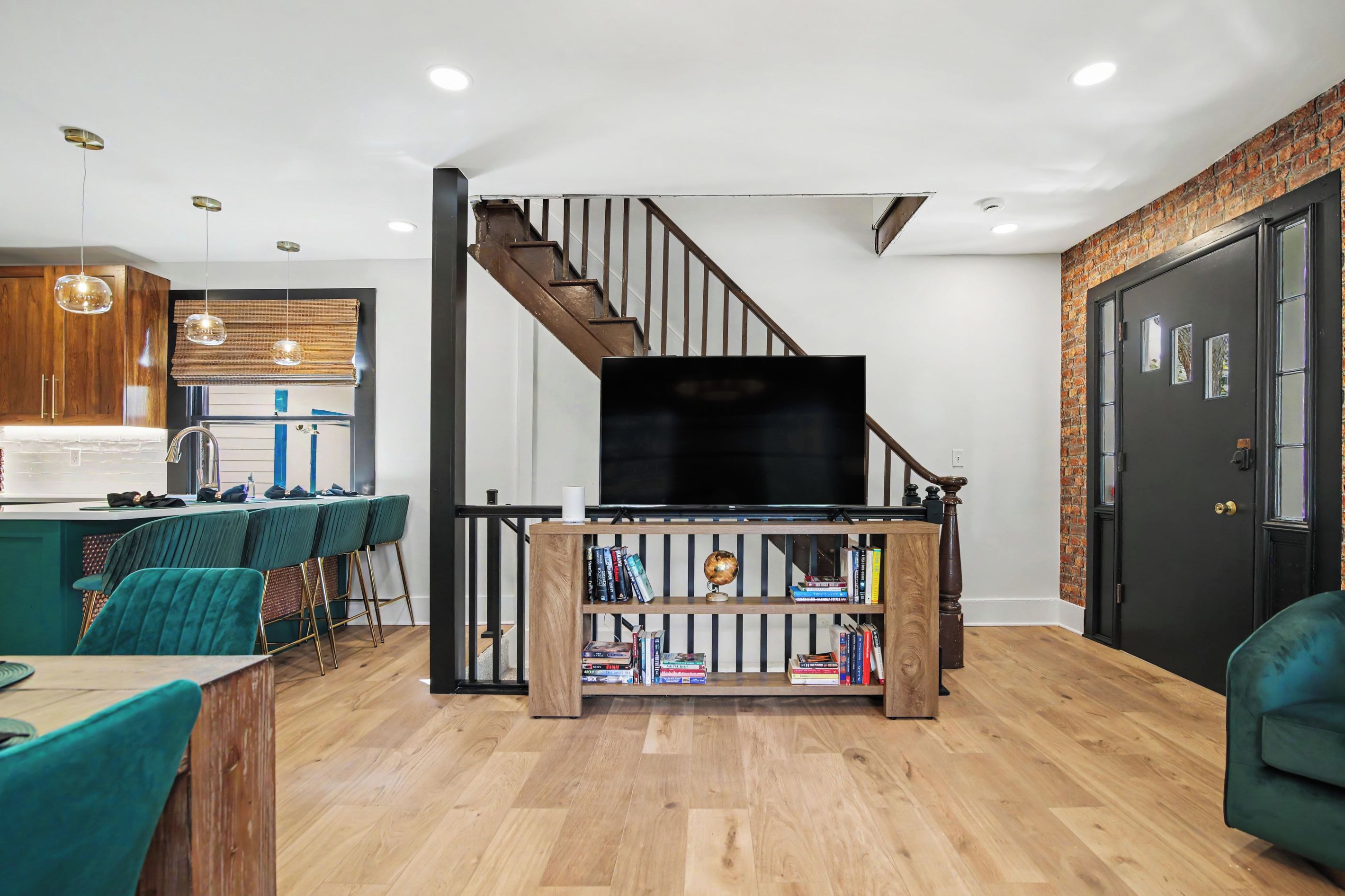 Un salon moderne avec un escalier, un coin repas avec des chaises de couleur turquoise et une bibliothèque.