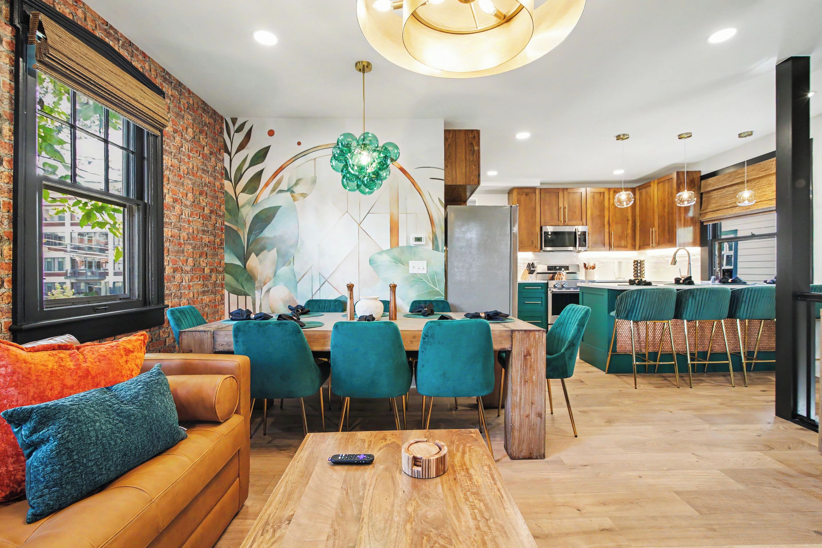 Une cuisine moderne dotée d’un îlot central, de meubles en bois et d’un coin repas avec des chaises de couleur turquoise.