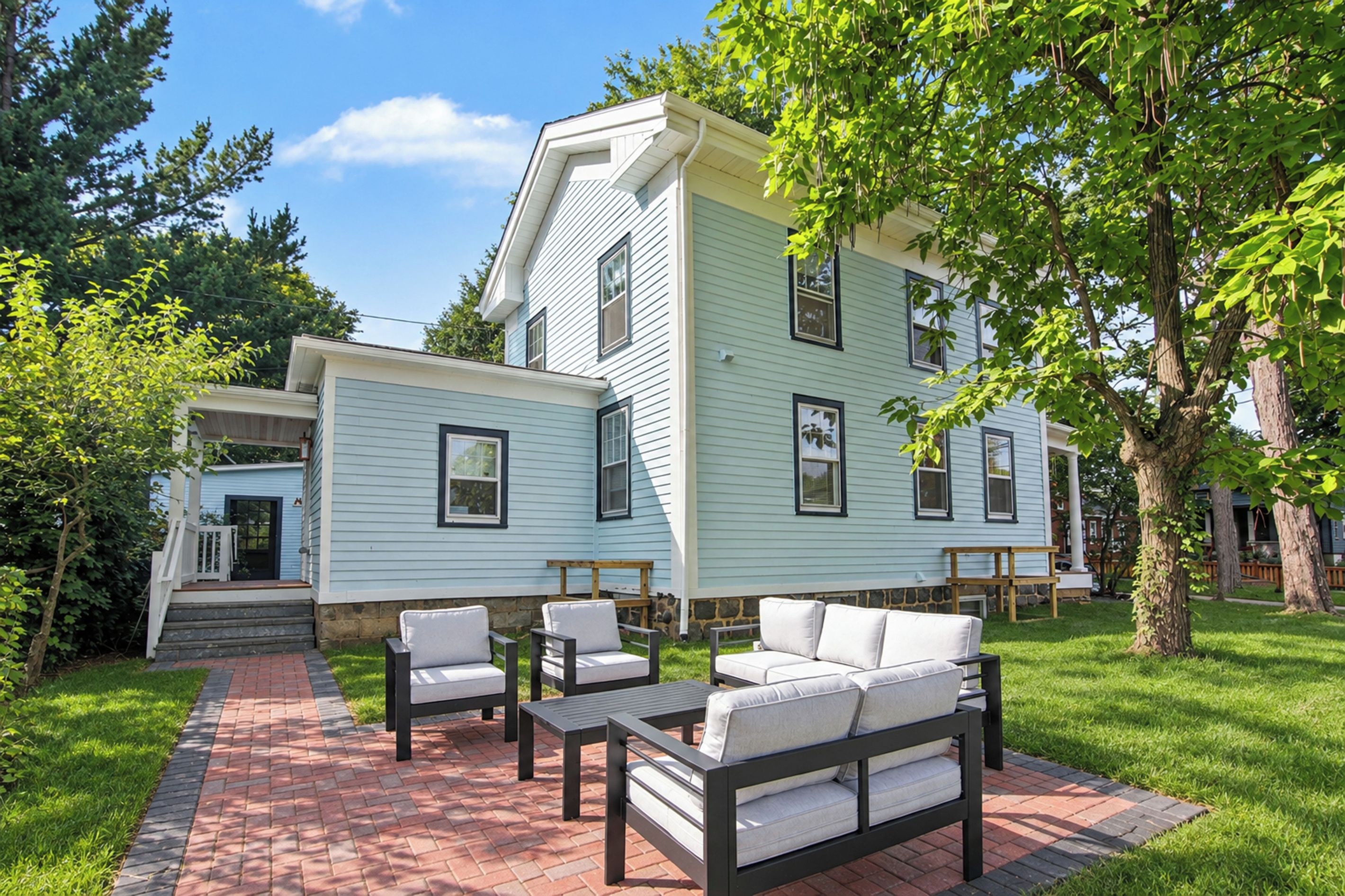 A two-story house with a patio area featuring outdoor furniture.