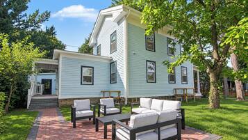 A two-story house with a patio area featuring outdoor furniture.