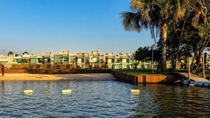 Un hôtel situé au bord de l’eau, doté d’une piscine, de palmiers et d’un pont.