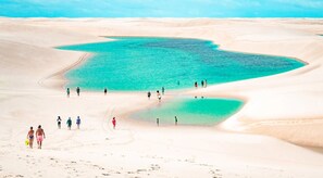 A desert landscape with a large turquoise pool surrounded by sand dunes. - Casa Condomínio Prime com Piscina Privativa - Barreirinhas/MA (Barreirinhas)
