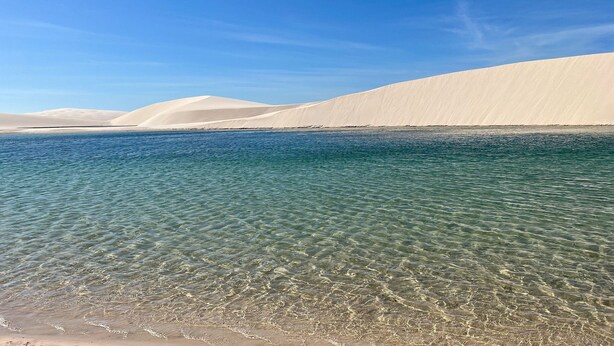 On peut clairement voir une plage avec des dunes de sable blanc et une eau calme.