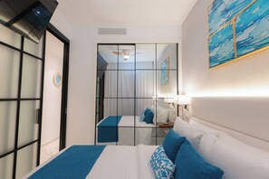 Ein Hotelzimmer mit Bett, Nachttisch, Spiegel und Deckenventilator.