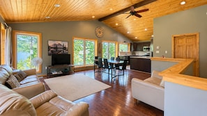 A spacious living area with a wooden ceiling, a dining table, and a kitchen area.