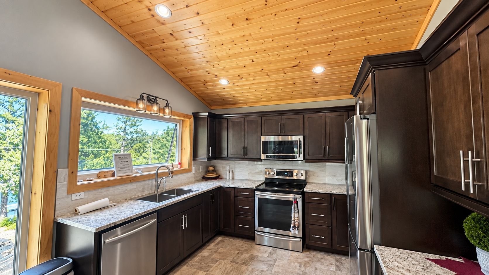 A modern kitchen with dark wood cabinets, stainless steel appliances, and a window with a view of greenery.
