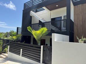 Uma casa moderna de dois andares com escada, cerca de madeira e plantas em vasos.