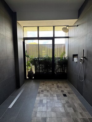 Ein modernes Badezimmer mit Dusche, einem Händetrockner und einem Blumentopf.