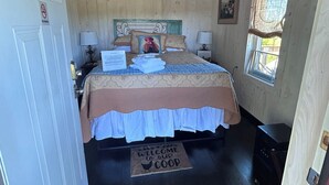 A bedroom with a bed, a ceiling fan, a window, a door, and a welcome mat. - Perfect 1-bedroom  off barn with AC in charming Petoskey (Petoskey)