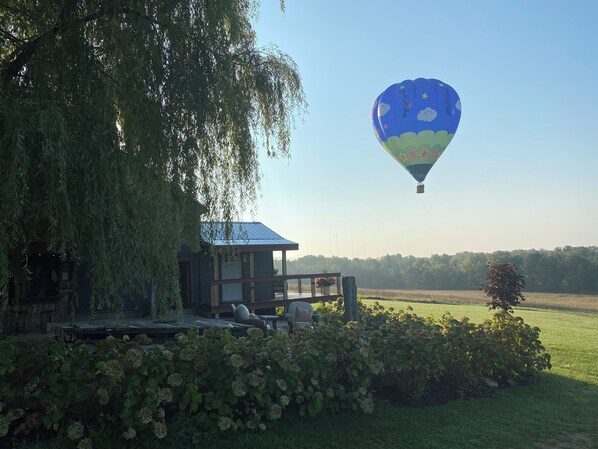 A hot air balloon, a wooden structure with a blue roof, and a grassy field.