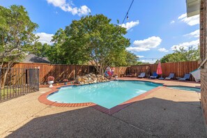 A backyard with a swimming pool, a wooden fence, and outdoor furniture. - Velvet Paradise-6 bdrm estate with pool, hot tub, tiki bar and firepit (Mesquite)