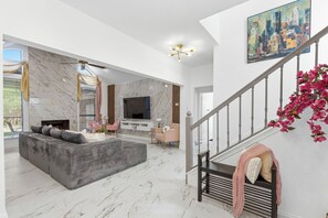 A spacious living area with a large sofa, a flat-screen TV, and a fireplace. - Velvet Paradise-6 bdrm estate with pool, hot tub, tiki bar and firepit (Mesquite)