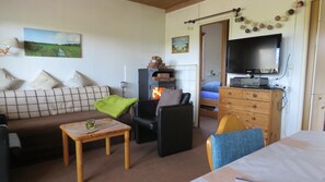 Une pièce confortable avec un canapé, un fauteuil, une table, un téléviseur et une cheminée.