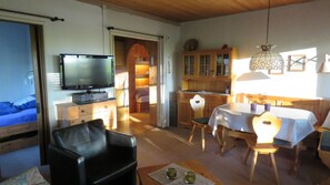 A cozy living room with a television, a dining area with a table and chairs, and a kitchen area with cabinets. - The perfect place to do nothing | A wooden house nestled between the forest and meadows (Geestland)