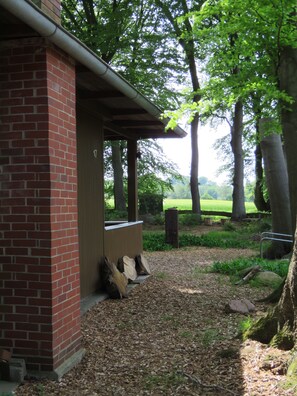 Un bâtiment en briques doté d’un porche couvert, d’un chemin de gravier et entouré d’arbres.