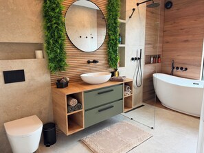 A modern bathroom with a wooden vanity, a large mirror, a white sink, a bathtub, and a shower.