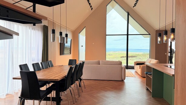 Een modern interieur met een eethoek, bank en grote ramen met uitzicht.