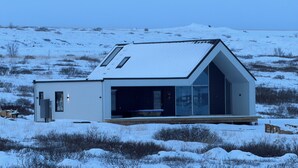 Een modern, gelijkvloers gebouw met een grote glazen gevel en een schuin dak, gelegen in een besneeerd landschap.