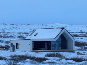A modern, single-story building with a large glass facade and a sloped roof, situated in a snowy landscape.