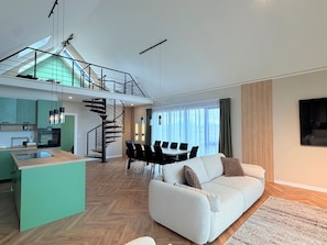 A spacious living area with a sofa, a dining table, and a kitchen in the background.