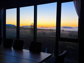 A conference room with a large table and chairs, overlooking a landscape with mountains and a clear sky.